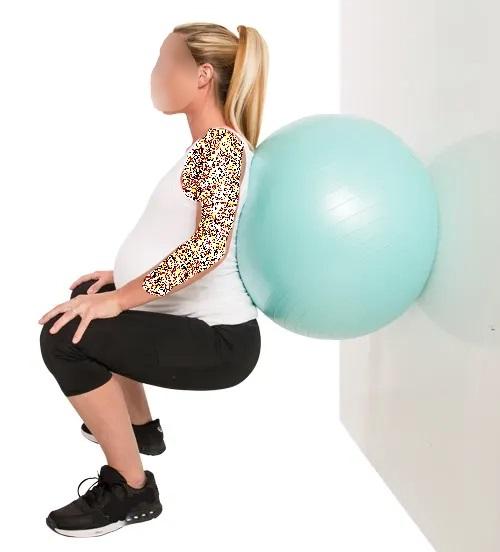 تمرینات ورزشی اسکات روی دیوار با توپ فیتنس برای تقویت عضلات کمر و کشاله در دوران بارداری